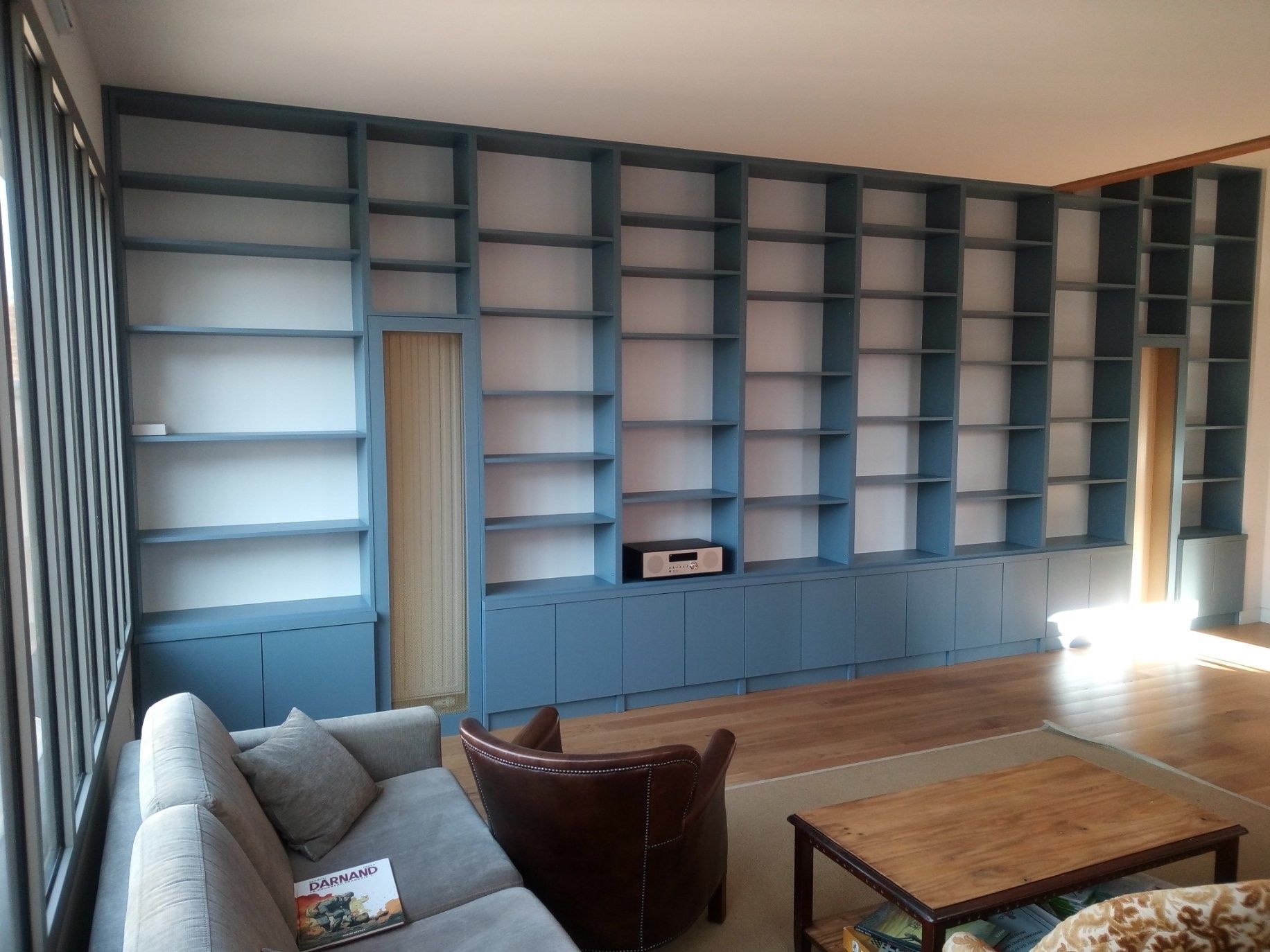 Immense bibliothèque bleue longeant tout un pan de mur du sol au plafond