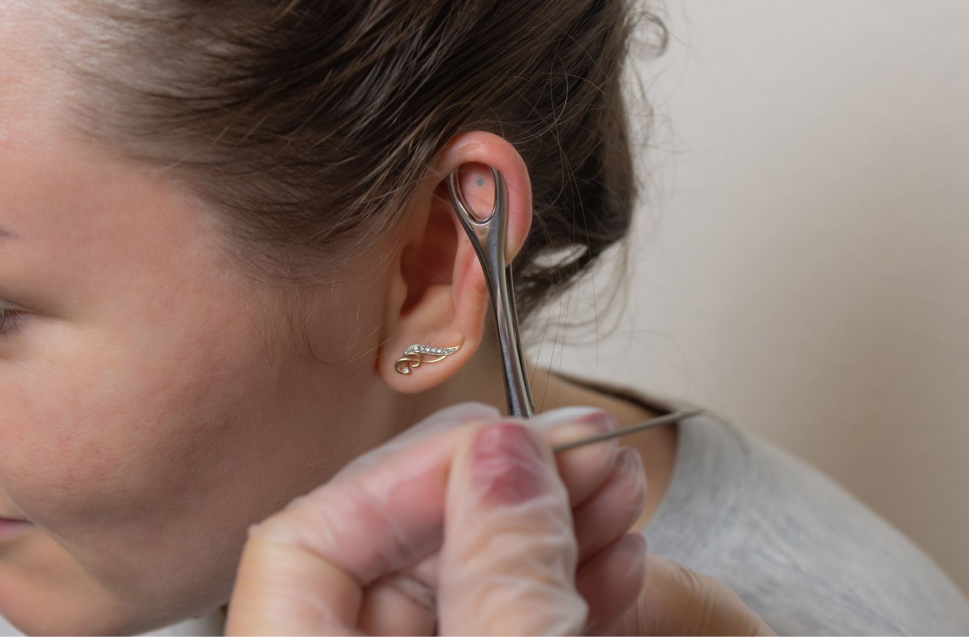 Una mujer se está haciendo perforar la oreja por un médico.