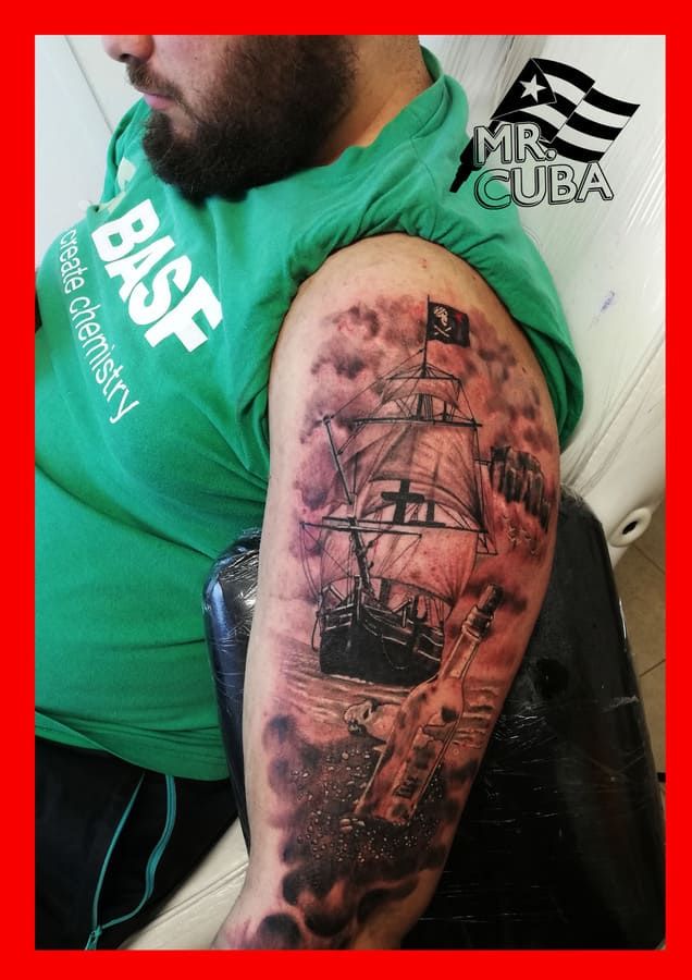 Un hombre tiene un tatuaje de un barco pirata en su brazo.