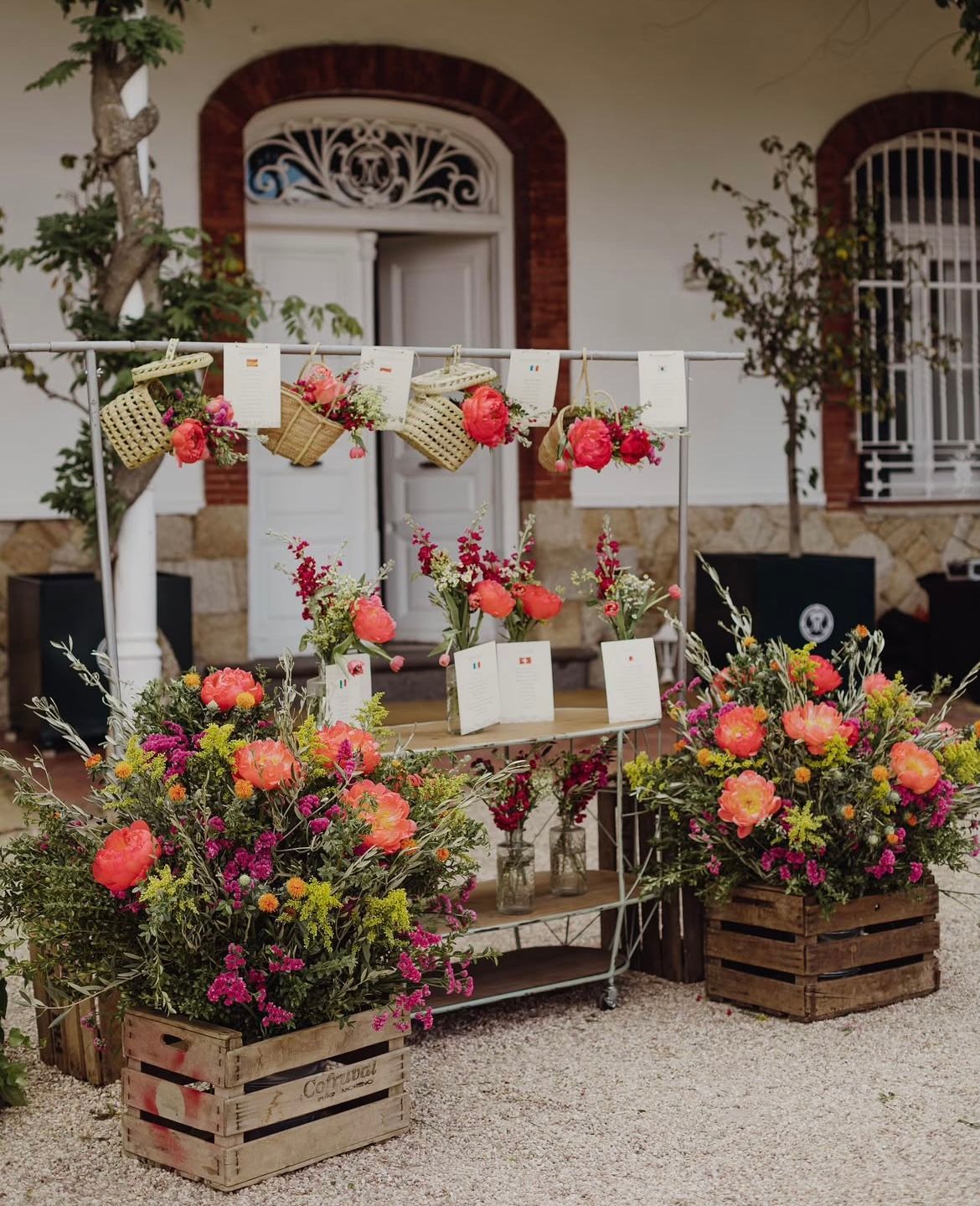 Una exhibición de flores en cajas de madera frente a un edificio.