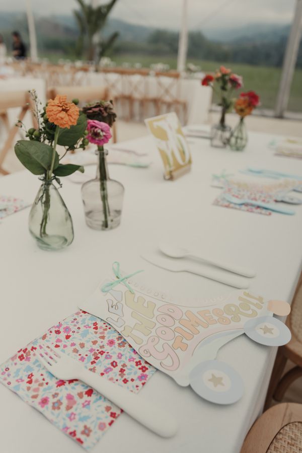 Una mesa preparada para una recepción de boda con flores en jarrones.