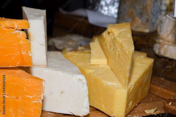 Assortiment de morceaux de fromage orange, blanc et jaune sur une planche à découper en bois