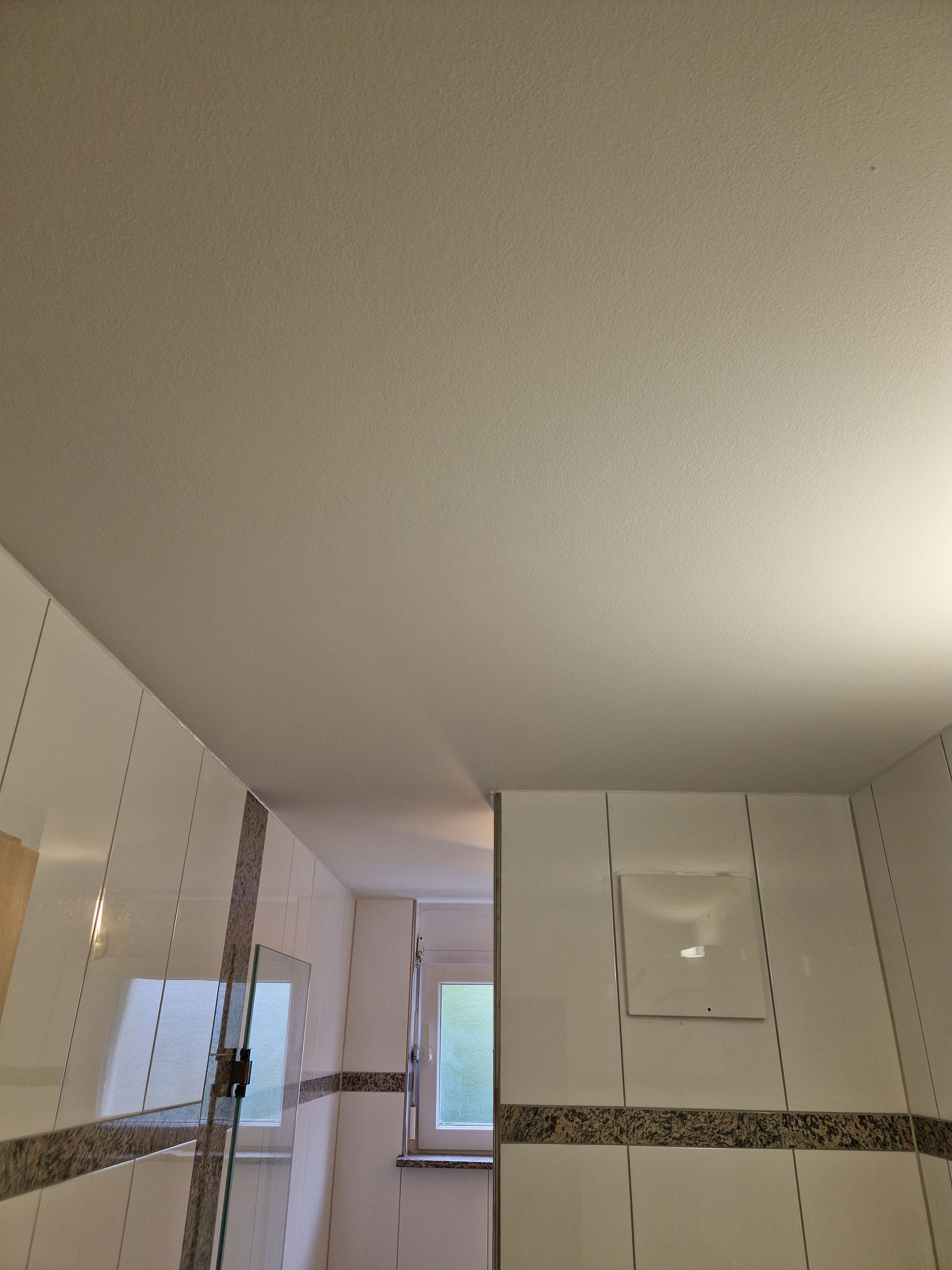 Ein Badezimmer mit weißen Fliesen und einer weißen Decke.