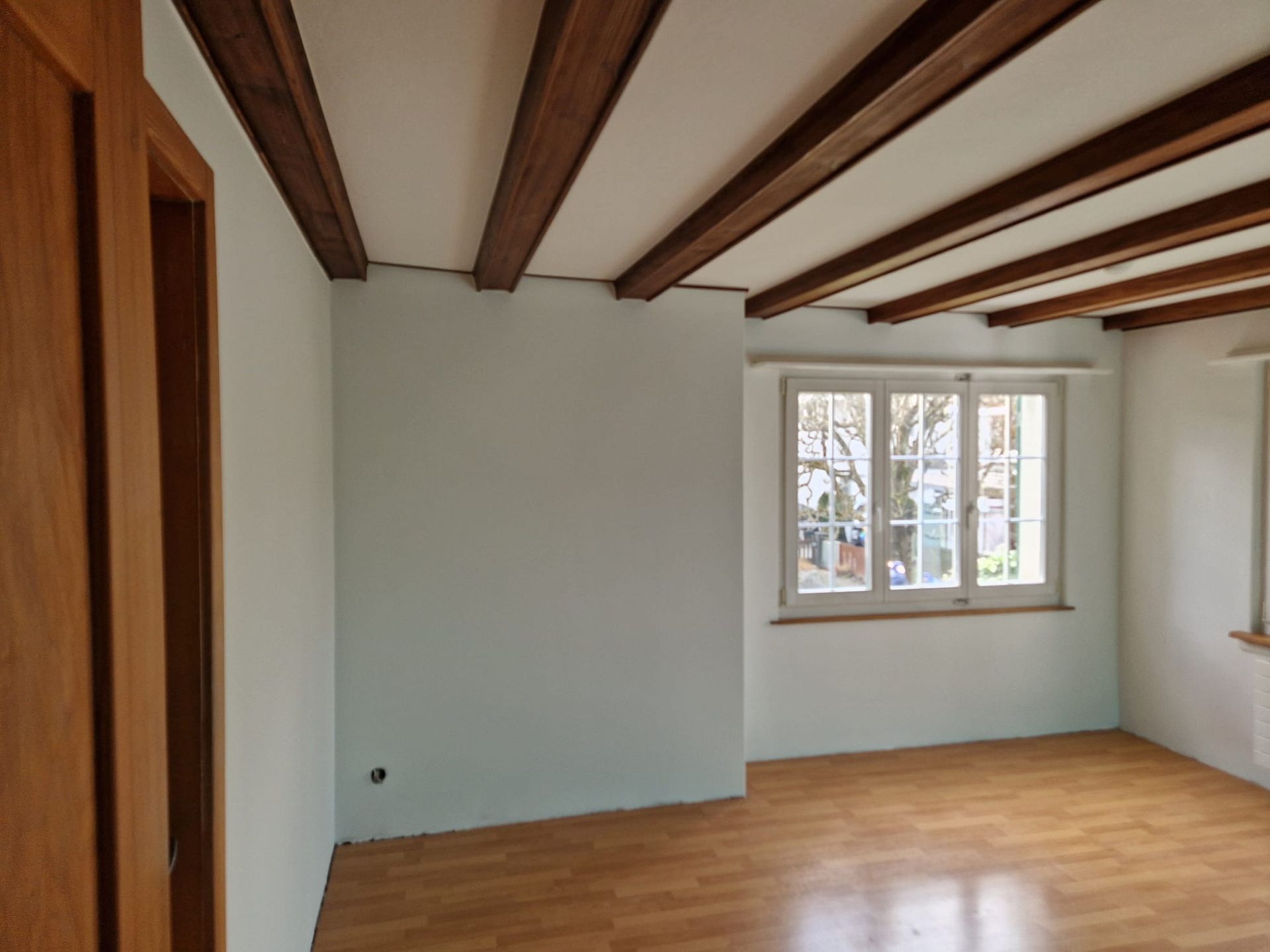 Ein leerer Raum mit Holzbalken und einem Fenster