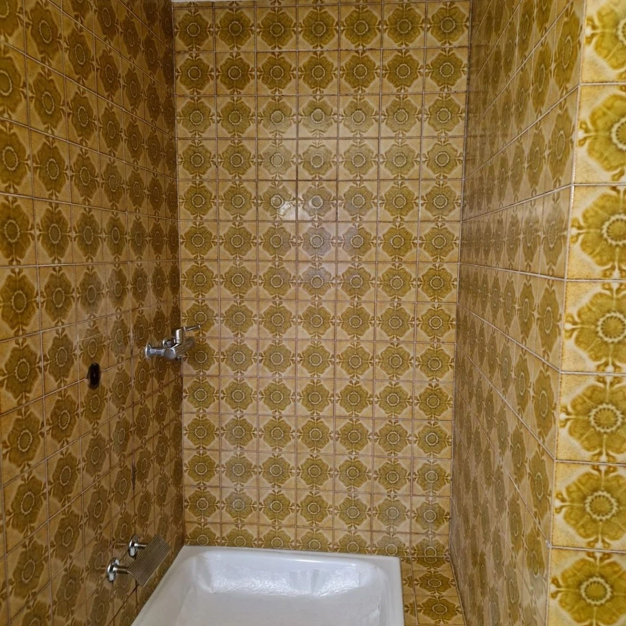 Ein Badezimmer mit gelben Fliesen und einer Badewanne