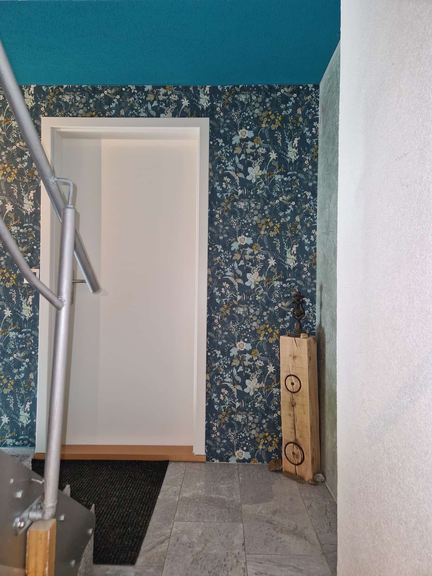 Ein Flur mit einer Treppe, die zu einer Tür hinaufführt, und einer blauen Decke.