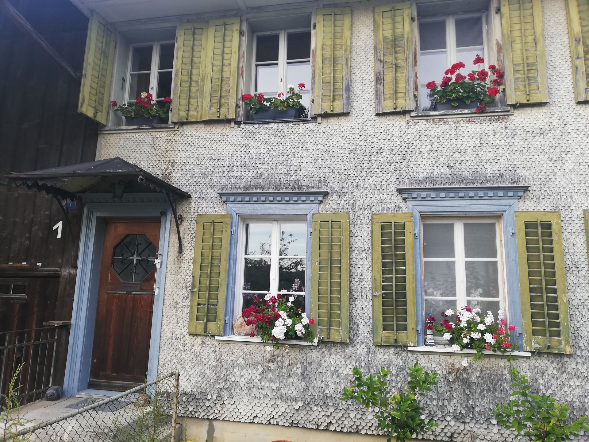 Die Vorderseite eines Hauses mit Blumen in den Fenstern