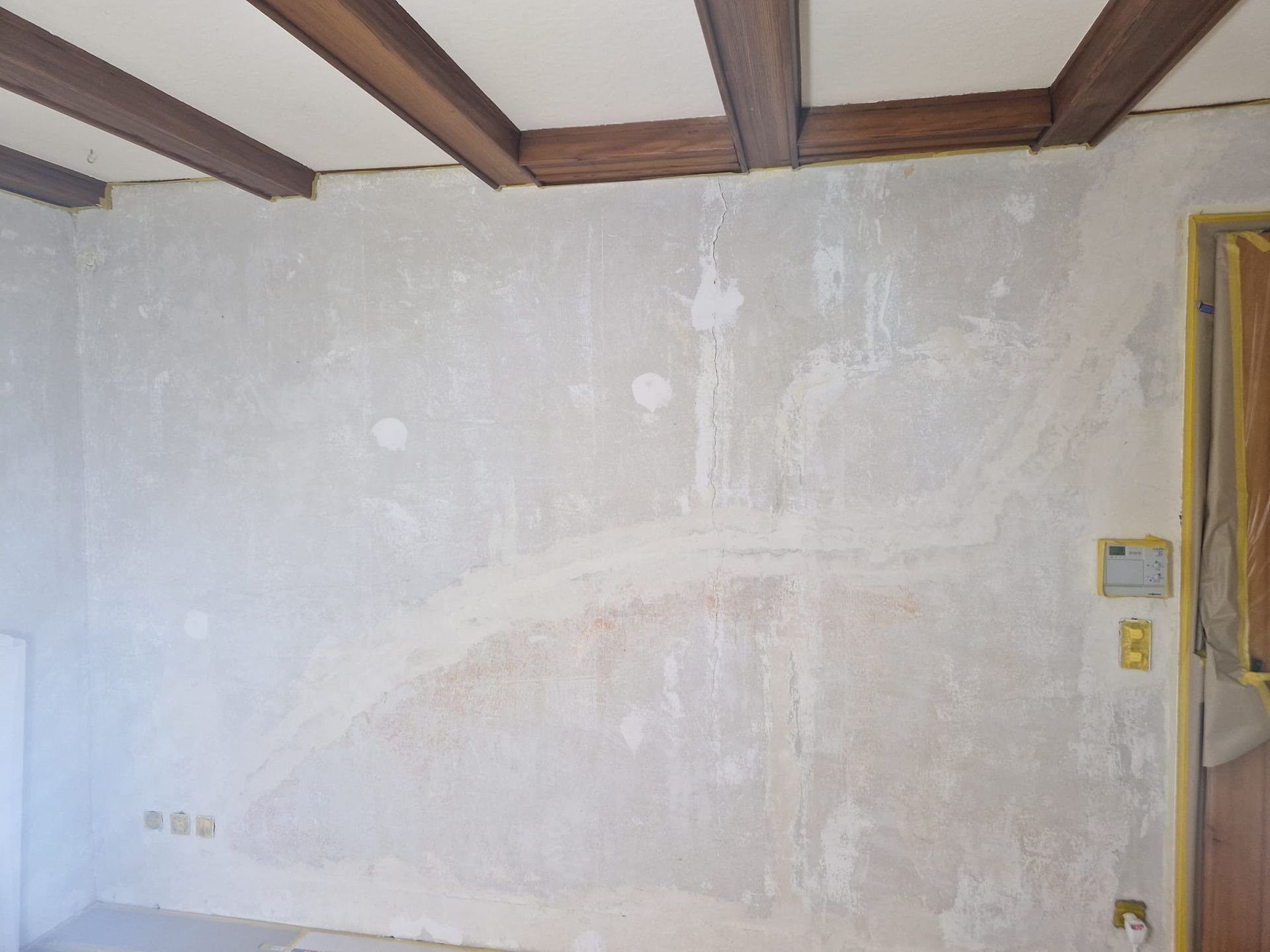 Ein Raum mit einer weißen Wand und Holzbalken an der Decke