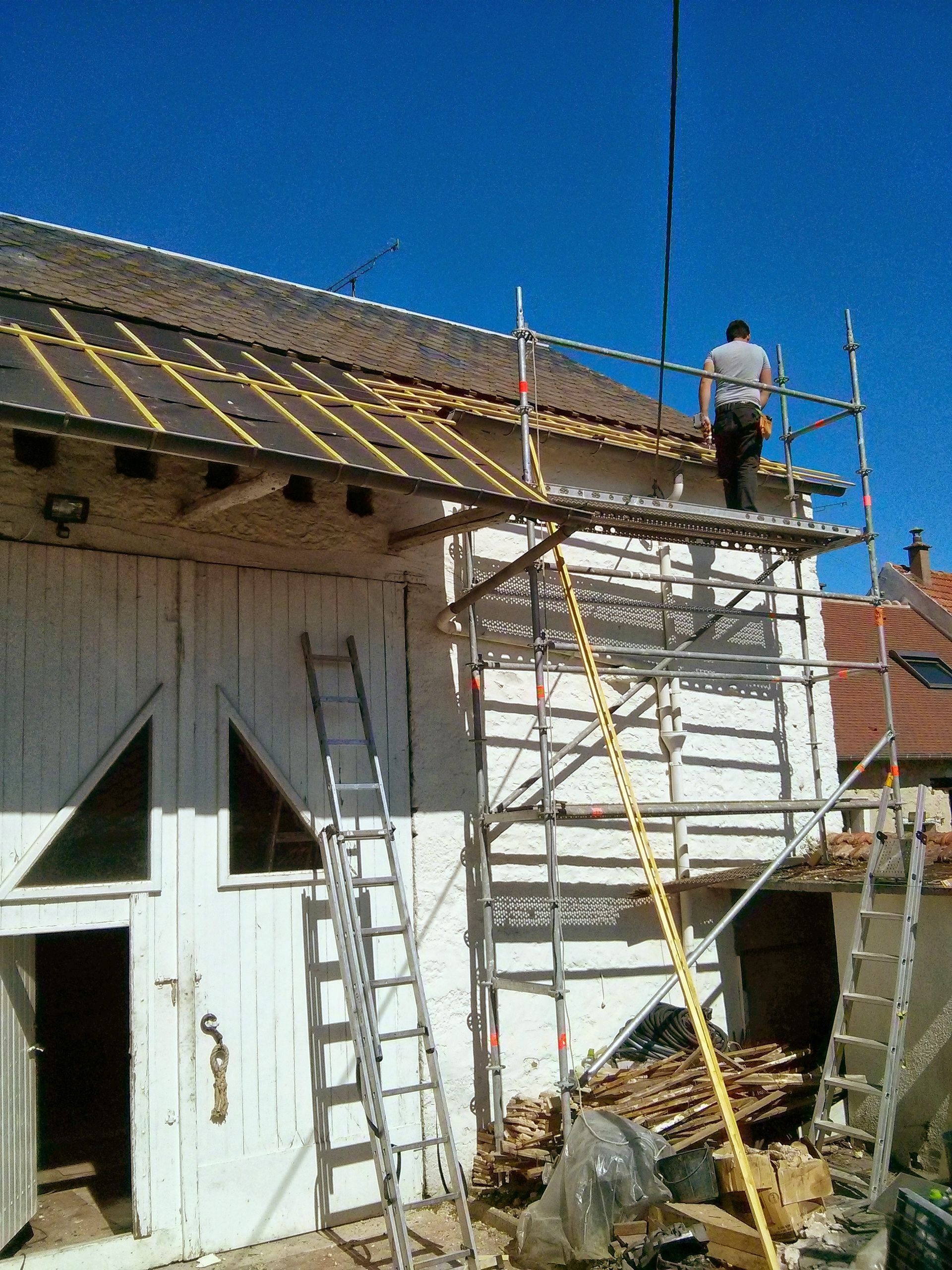 Un couvreur sur un échafaudage et un toit en rénovation