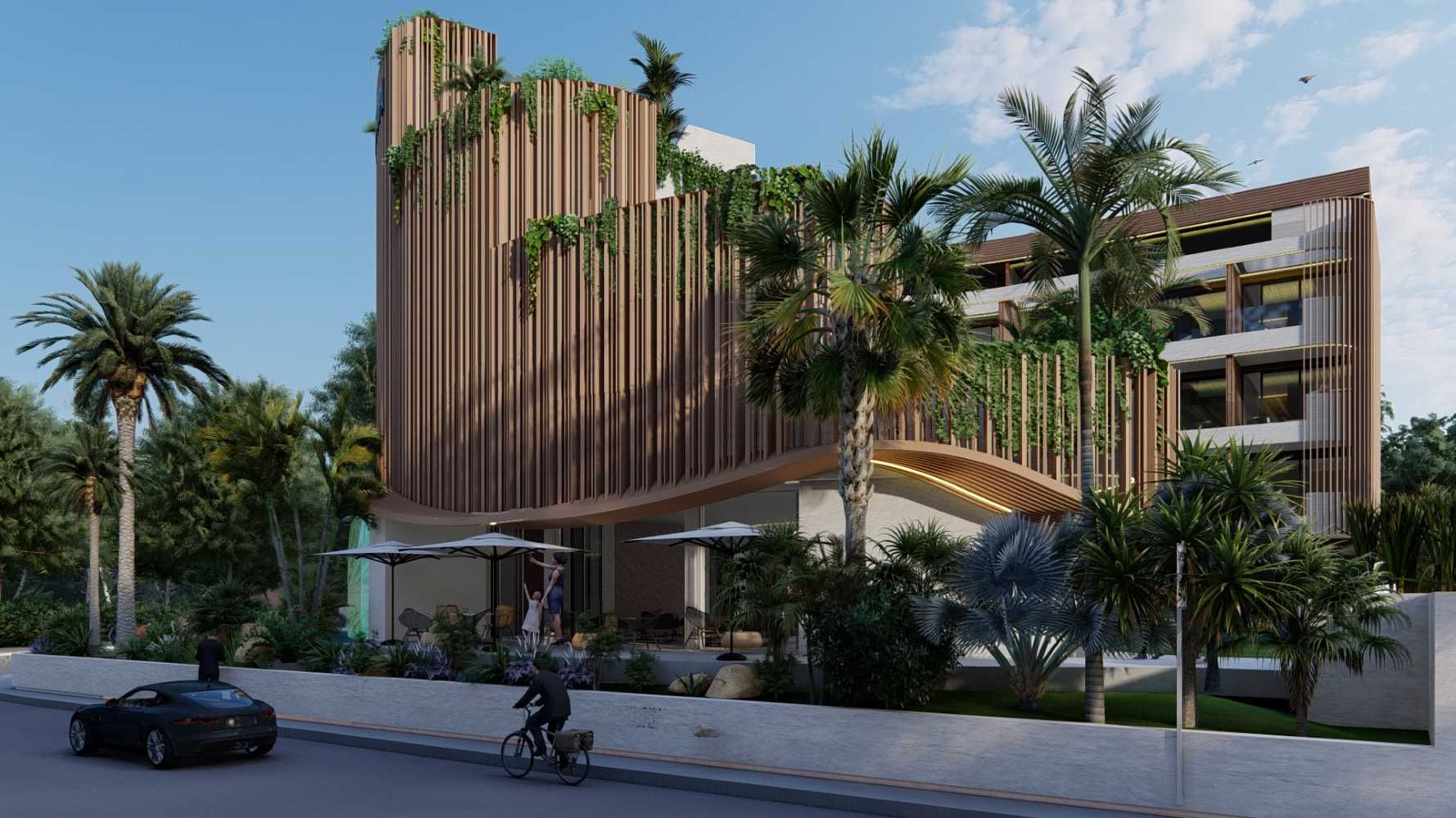 Un hombre va en bicicleta delante de un gran edificio rodeado de palmeras.