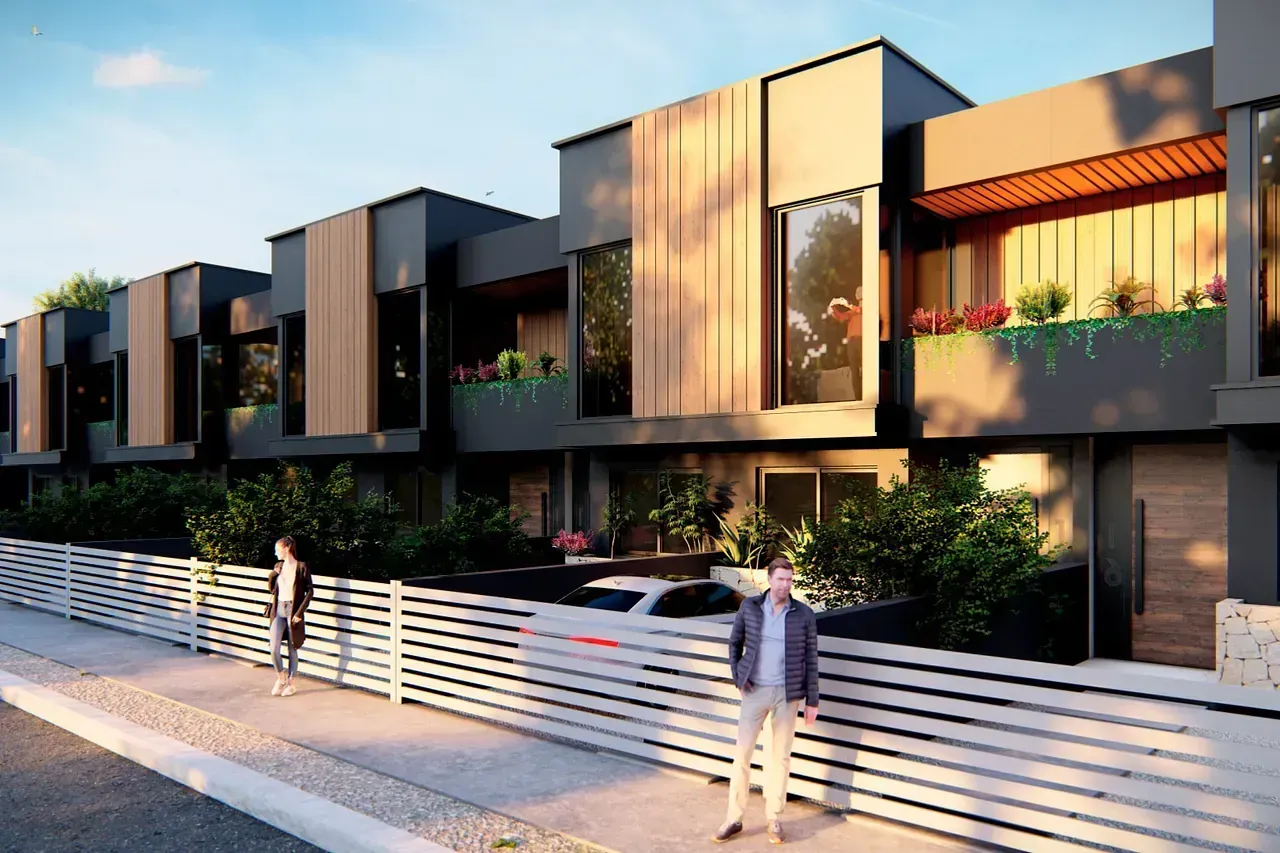 Un hombre está parado en la acera frente a una hilera de casas.