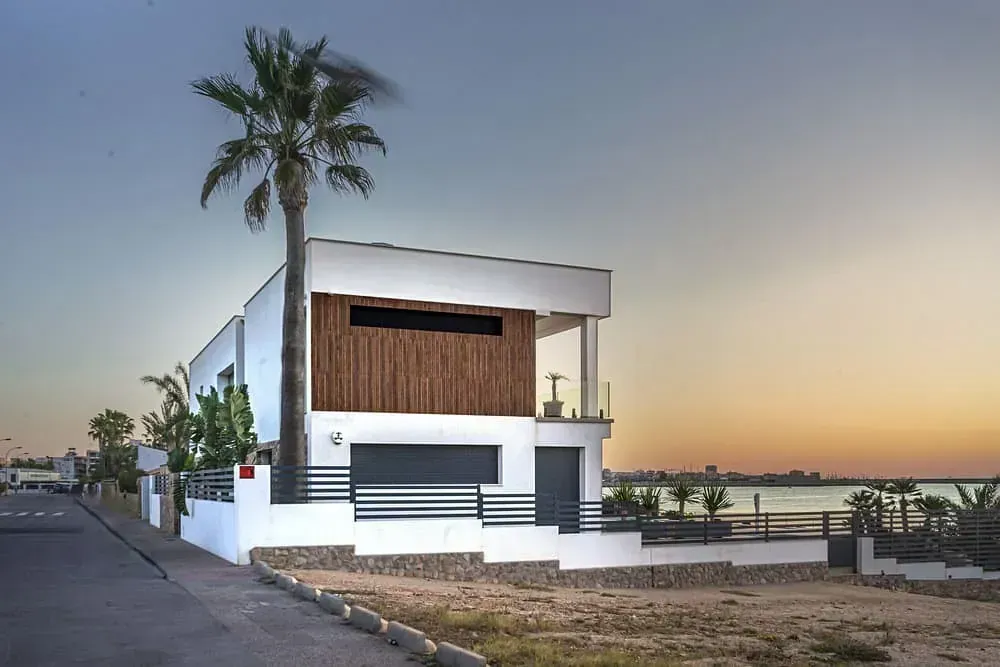 Una casa blanca con una palmera delante de ella.
