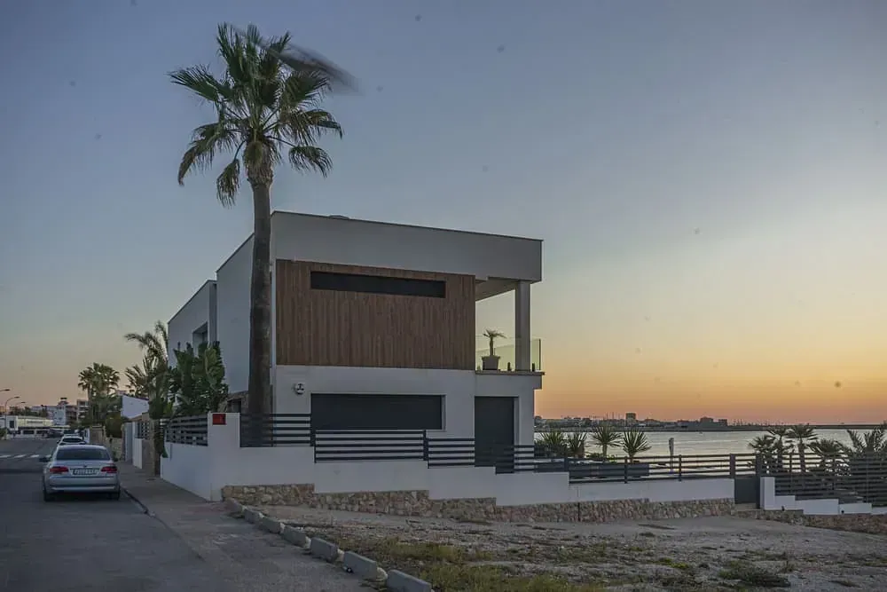 Un coche está aparcado delante de una casa con una palmera al fondo.
