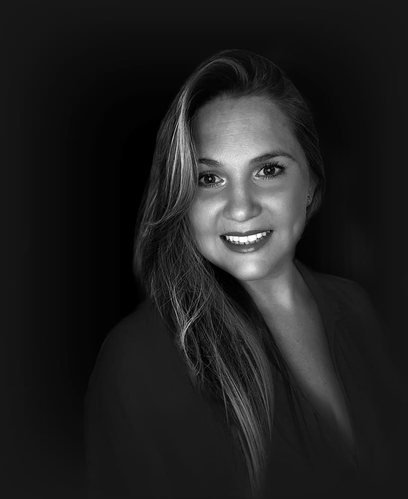 Una mujer con cabello largo sonríe en una foto en blanco y negro.