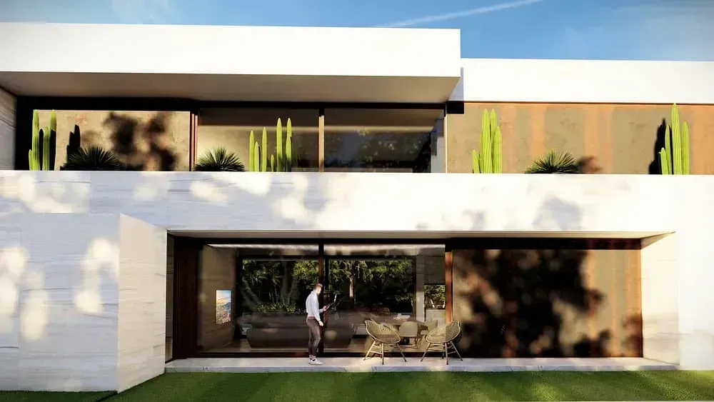 Un hombre está parado frente a una casa moderna con muchas ventanas.