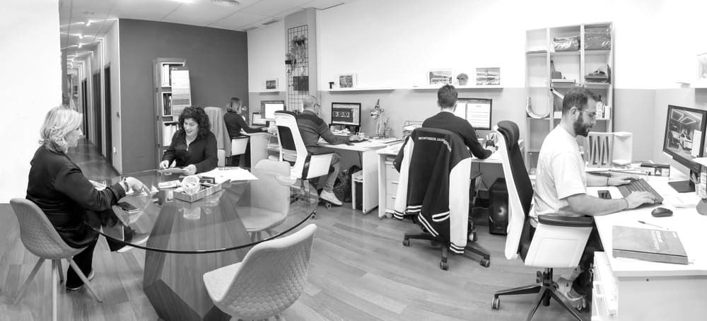 Un grupo de personas están sentadas en escritorios en una oficina.