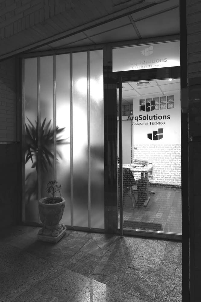 Una fotografía en blanco y negro de una puerta con una planta delante de ella.