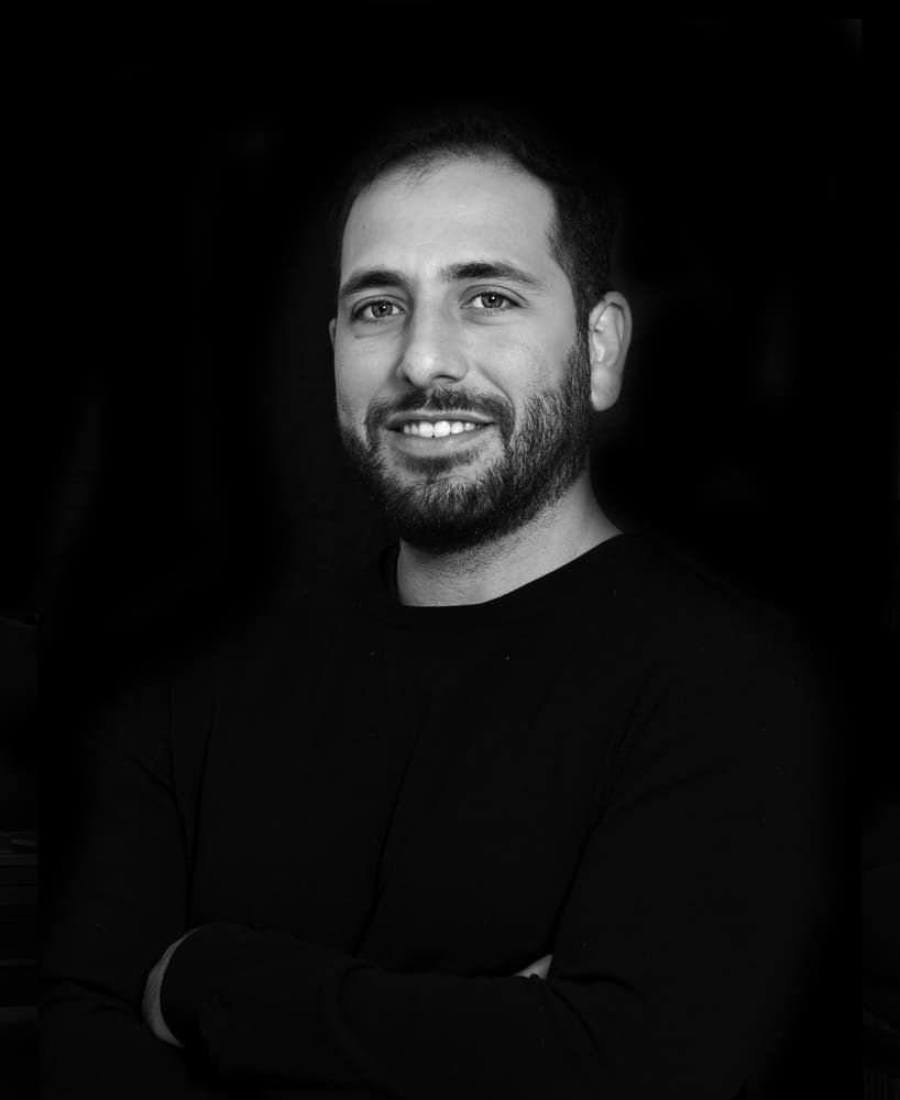 Un hombre con barba sonríe en una foto en blanco y negro.
