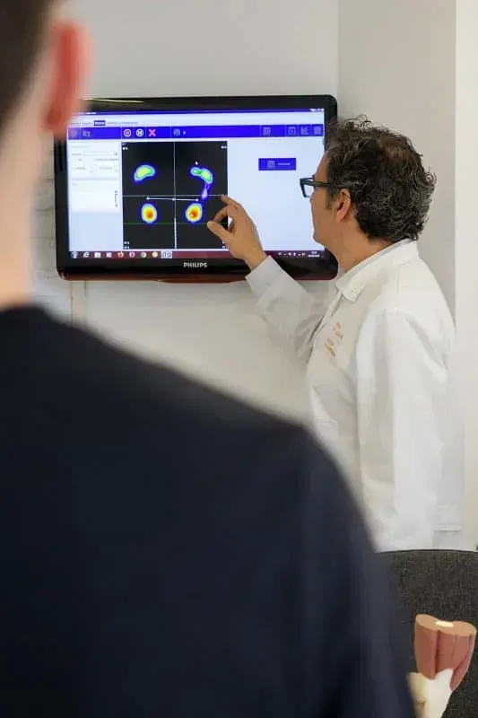 Un médico señala una pantalla de computadora mientras un paciente observa.