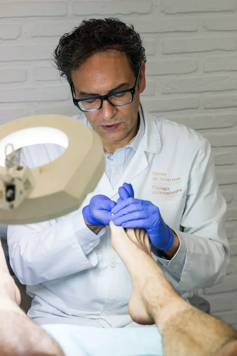 Un médico está examinando el pie de un paciente bajo una lupa.