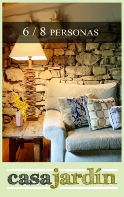 Una sala de estar con un sofá y una lámpara frente a una pared de piedra.