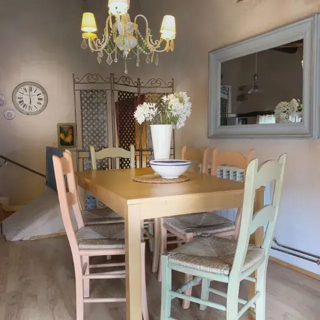 Comedor con mesa y sillas de madera, candelabro, espejo, flores y reloj.
