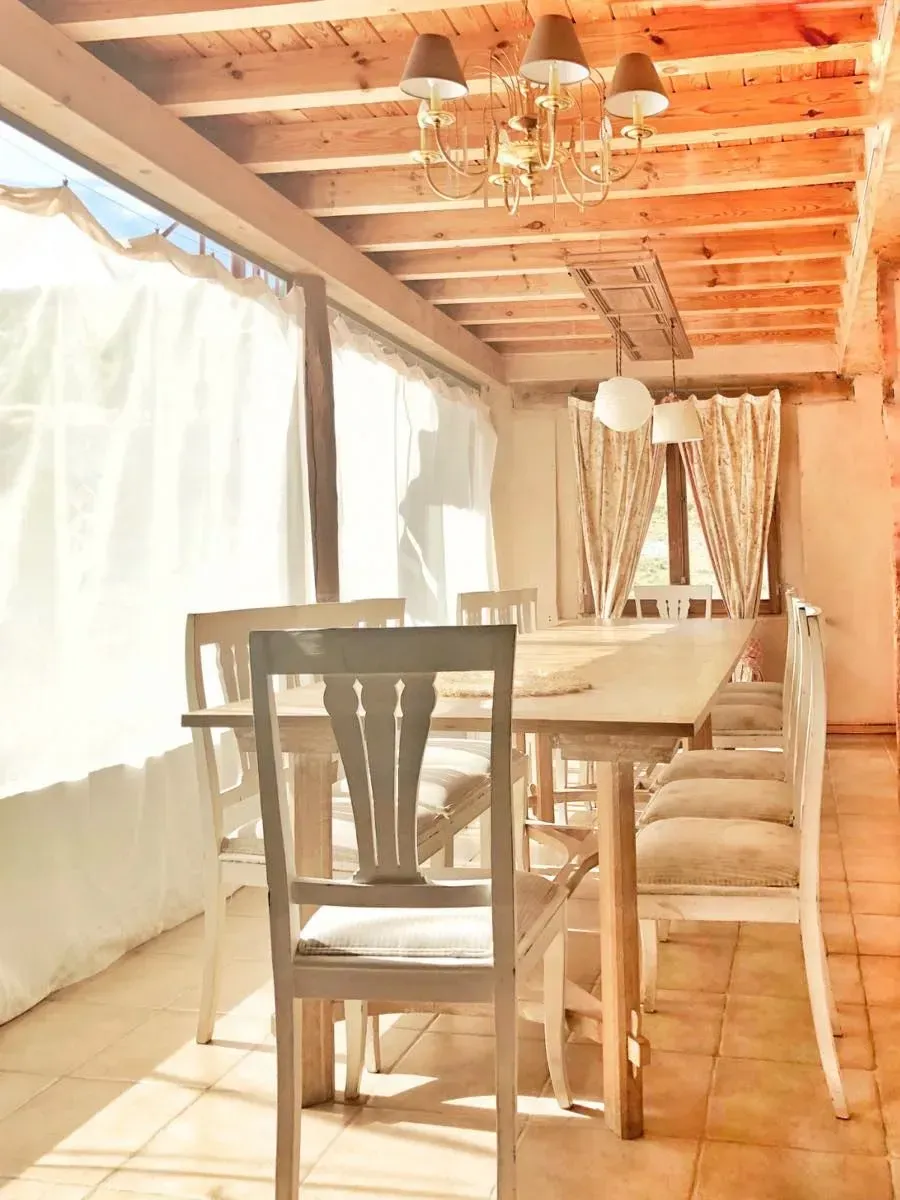 Comedor con mesa y sillas de madera, luz solar entrando por la ventana.