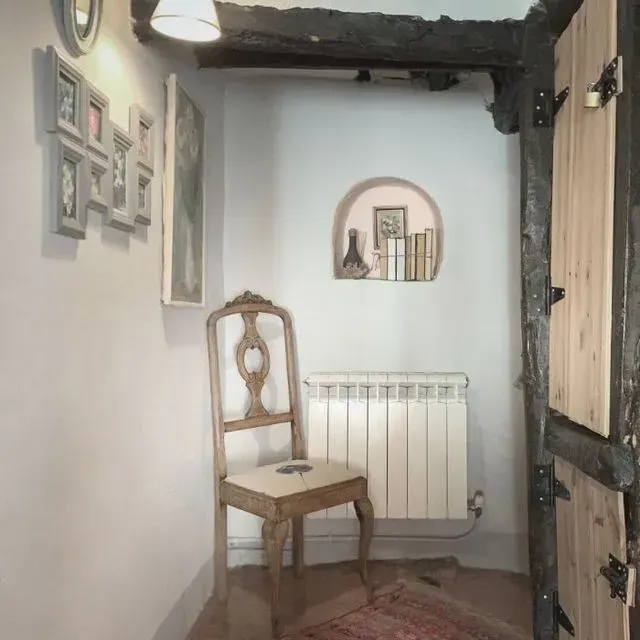 Pasillo con silla decorativa, obra de arte y estantería empotrada con libros y objetos.