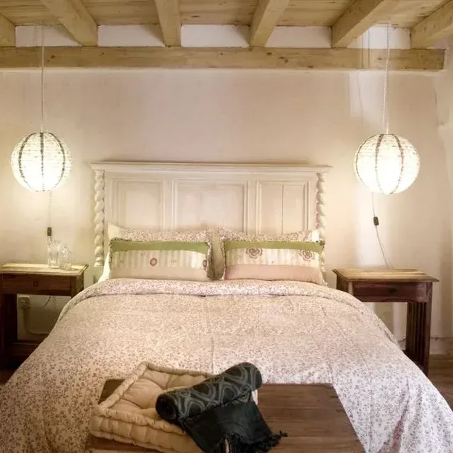 Dormitorio con una cama blanca, mesitas de noche de madera y faroles de papel colgando de un techo de madera.