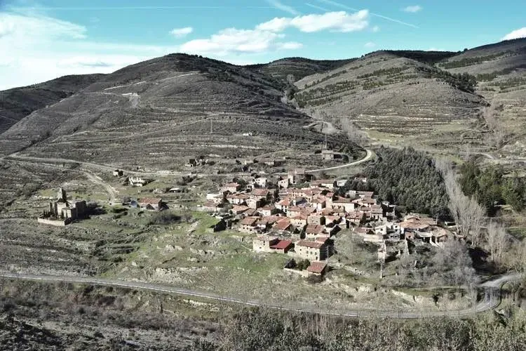 Una vista aérea de un pequeño pueblo en medio de un valle rodeado de montañas.