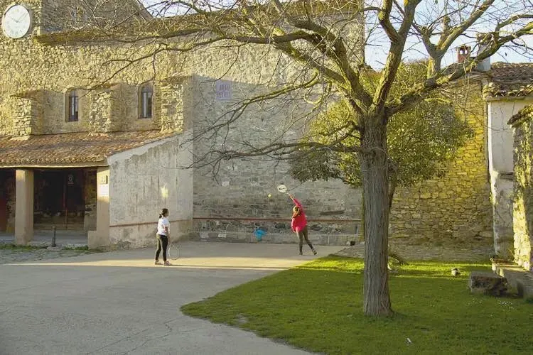 Dos personas están jugando voleibol frente a un edificio de piedra.