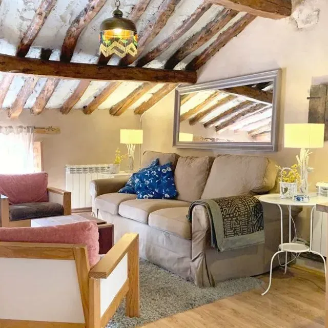 Acogedora sala de estar con sofá beige, dos sillones, vigas de madera y un gran espejo.