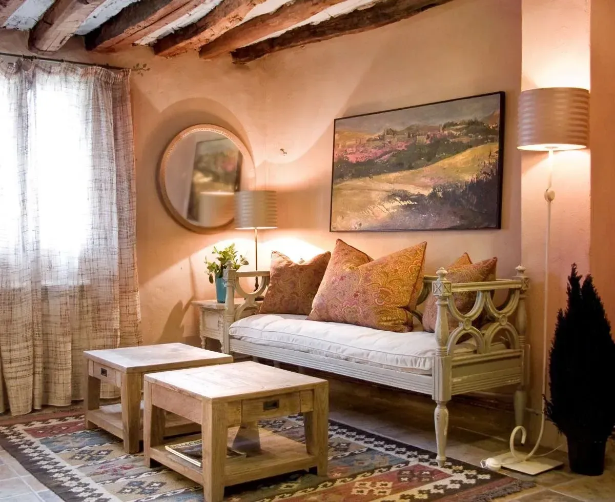 Sala de estar con paredes de color rosa pálido, un banco beige y una alfombra colorida.