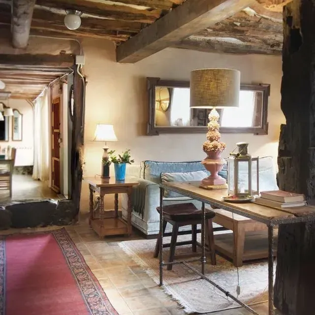Sala de estar rústica con vigas a la vista, muebles acogedores e iluminación cálida.