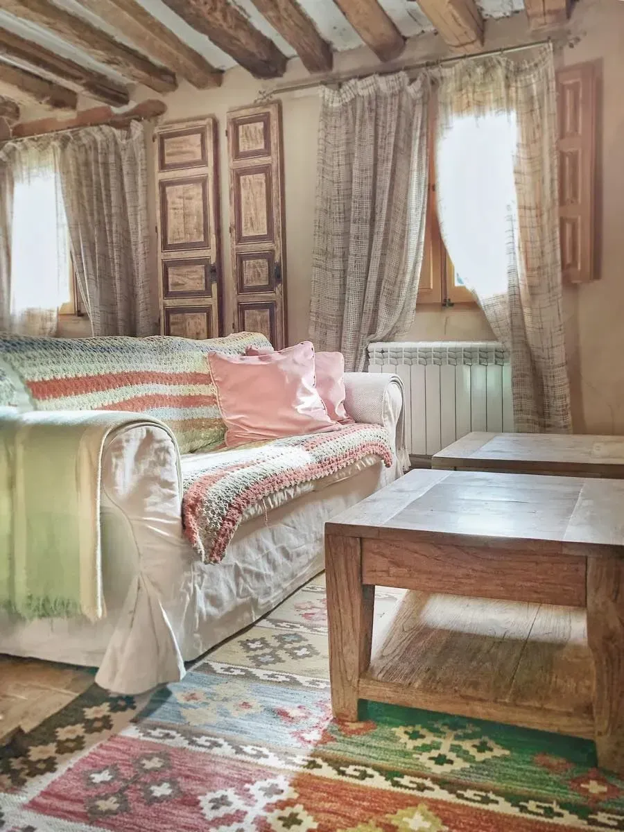 Acogedora sala de estar con sofá, alfombra estampada, mesas de madera y detalles rústicos.