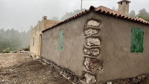 Una pequeña casa con techo de tejas y contraventanas verdes en las ventanas.