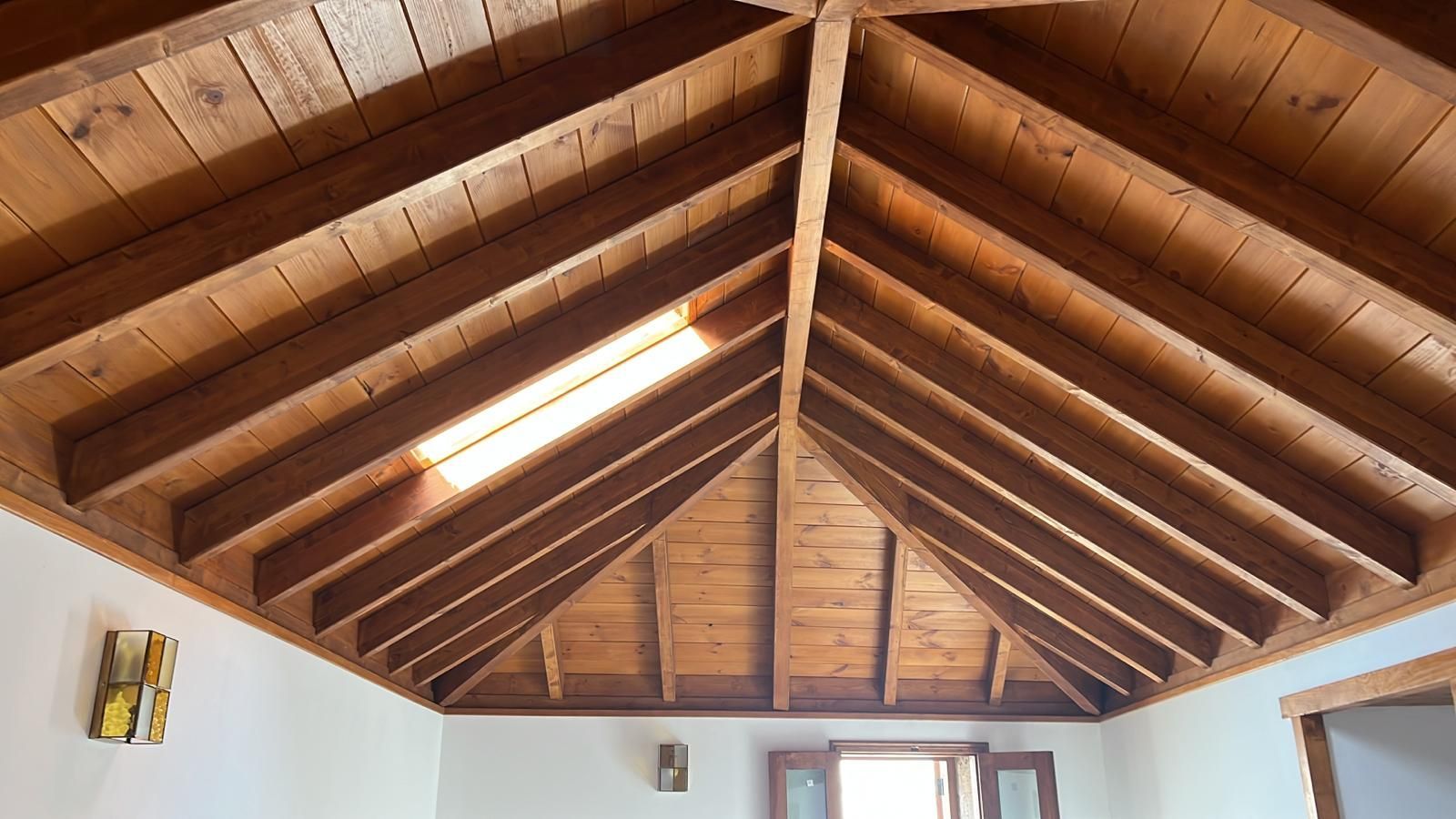 Una habitación con techo de madera y una ventana