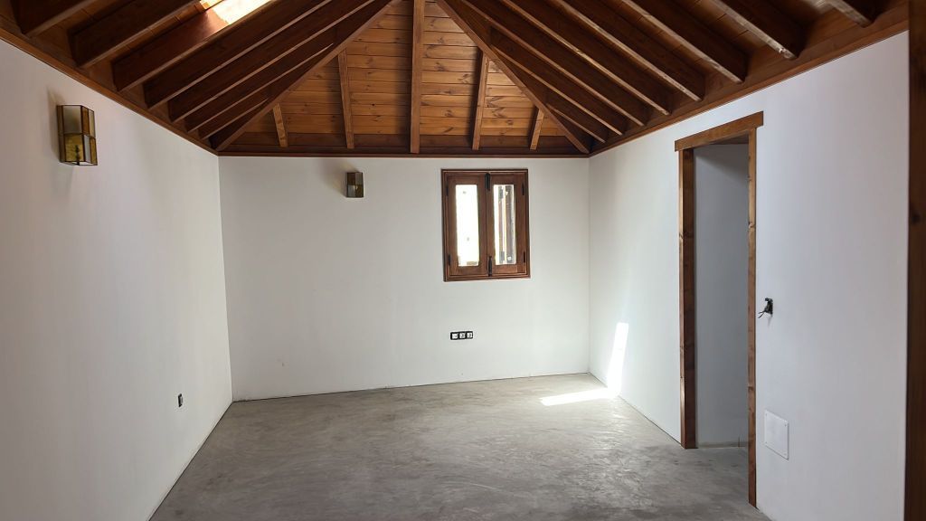 Una habitación vacía con un techo de madera y una ventana.