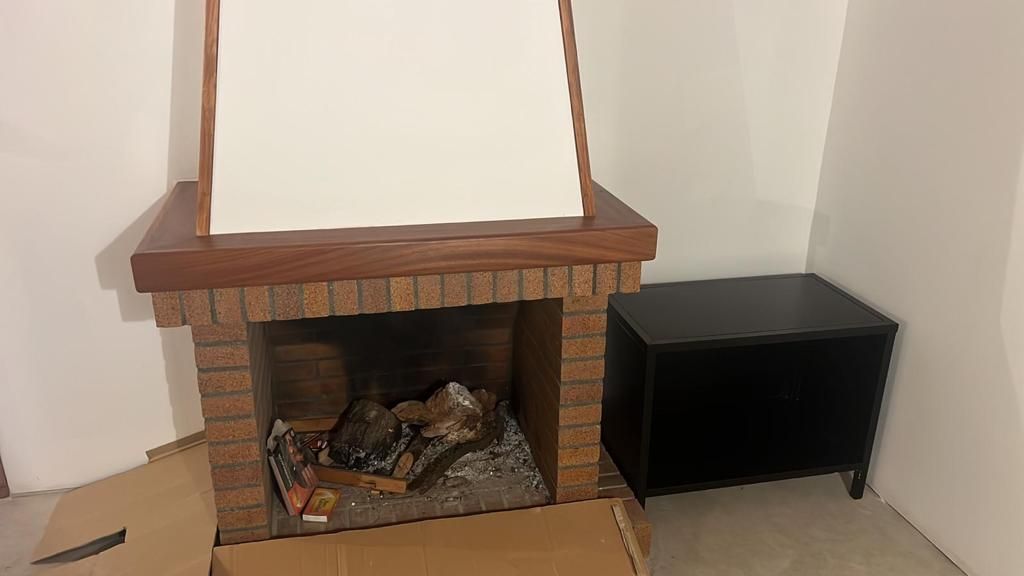 Una chimenea de ladrillo está situada en un rincón de una habitación al lado de una caja negra.