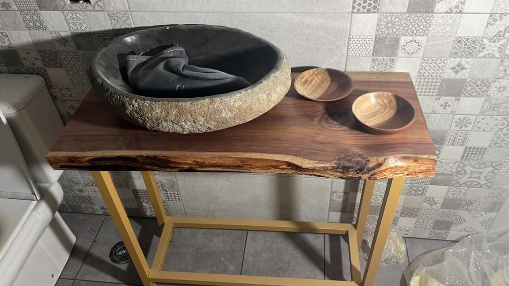 Un lavabo está colocado encima de una mesa de madera en un baño.