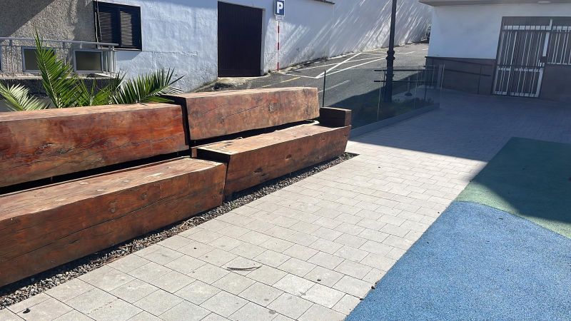 Un banco de madera está sentado en una acera de ladrillos frente a un edificio.