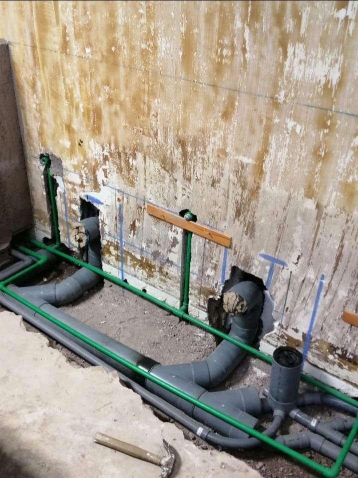 Un montón de tuberías están tendidas en el suelo delante de una pared.