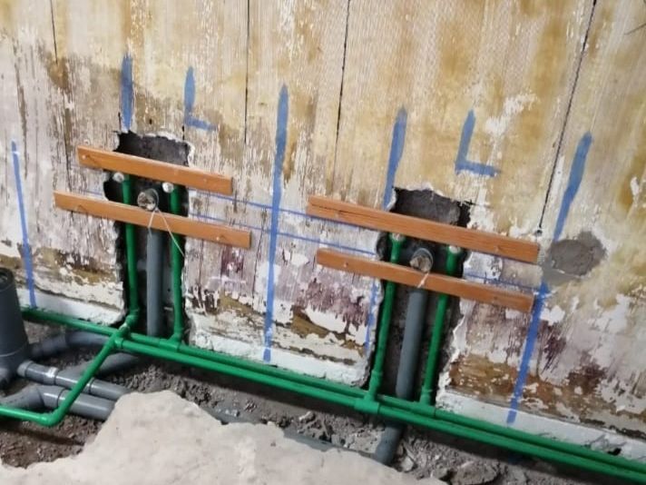 Se están instalando tuberías verdes en un agujero en una pared.