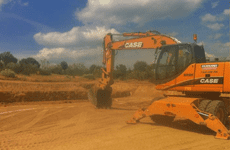 Una excavadora está sentada encima de un campo de tierra.