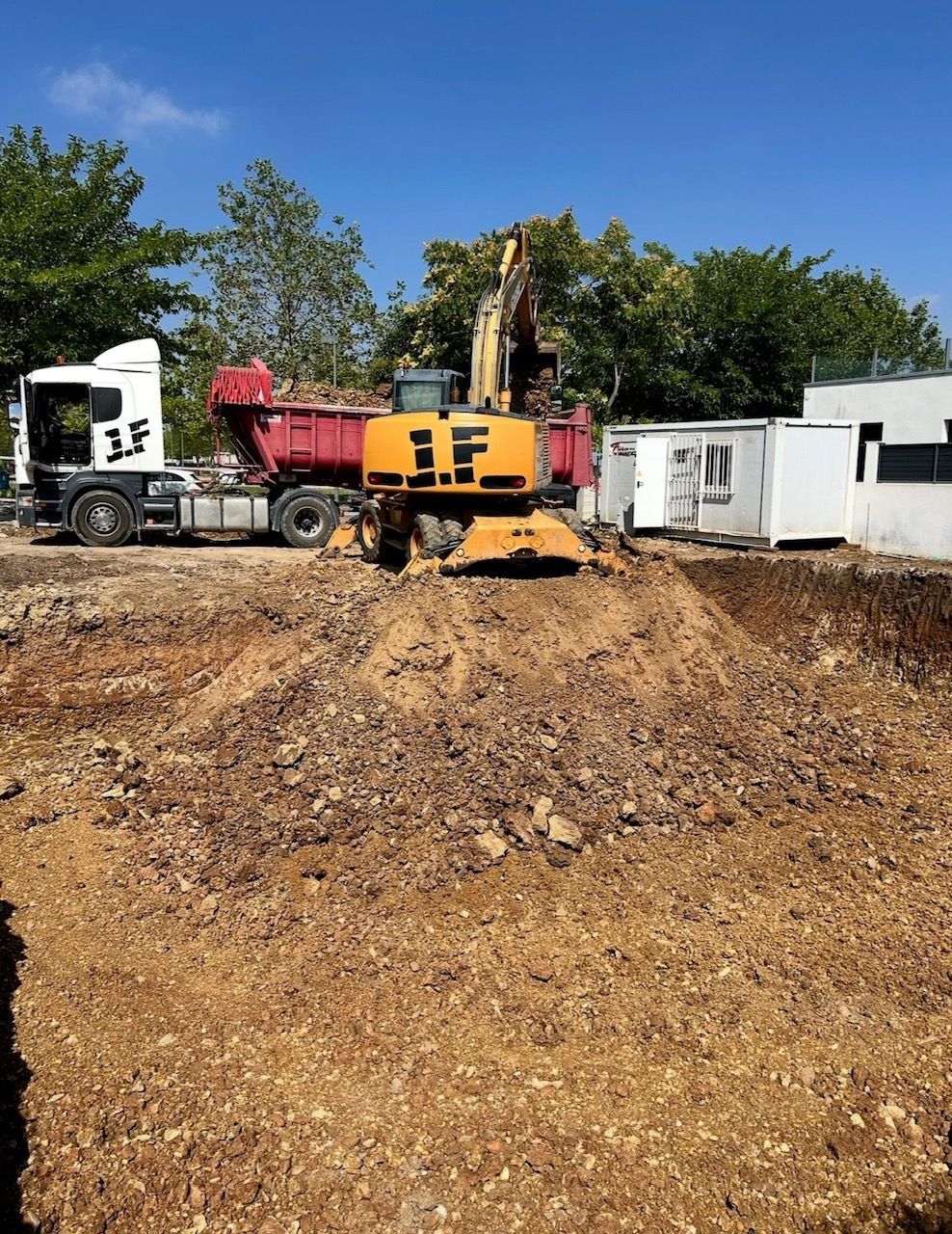 Una excavadora y una retroexcavadora están trabajando en un sitio de construcción.