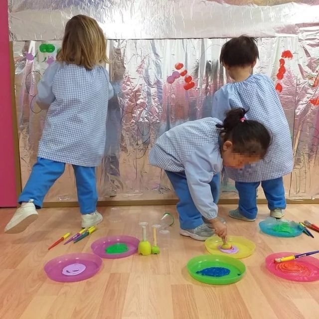 Un grupo de niños está jugando con platos de colores en el suelo.