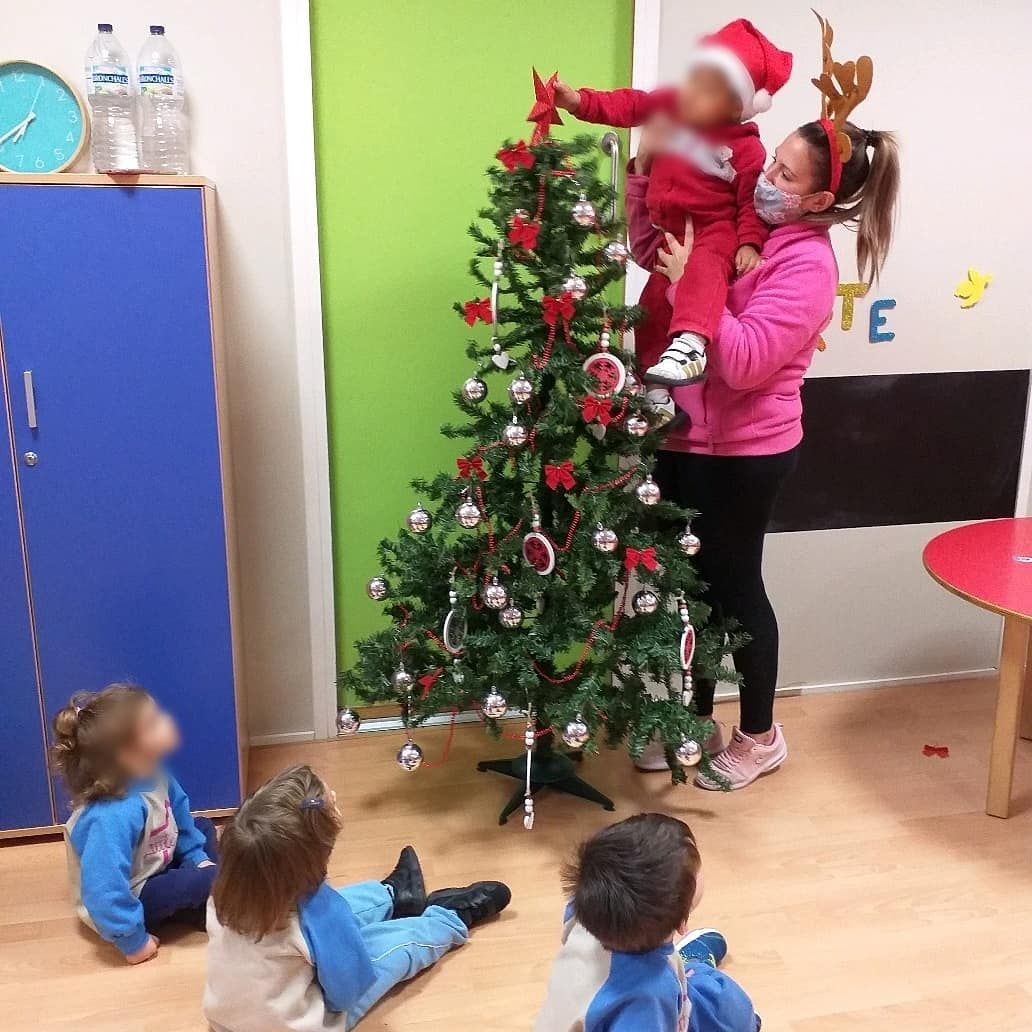 Una mujer sostiene a un niño frente a un árbol de Navidad.