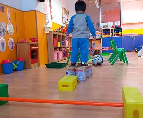 Un niño está parado sobre una caja amarilla en una sala de juegos.