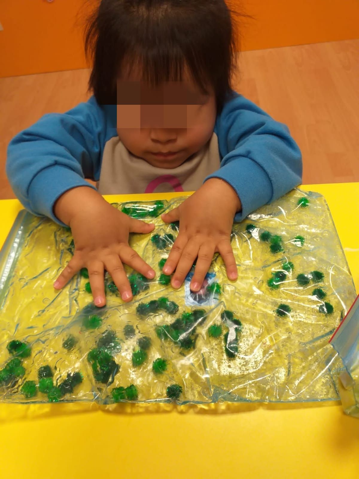 Un niño está jugando con una bolsa de plástico llena de canicas verdes.