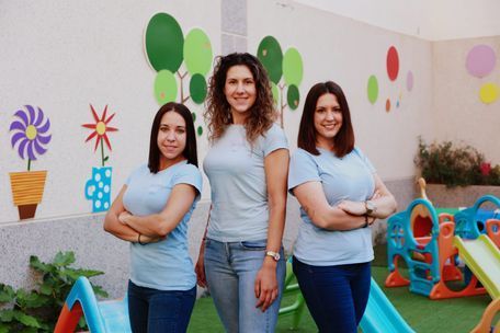 Tres mujeres posan para una fotografía delante de un tobogán.